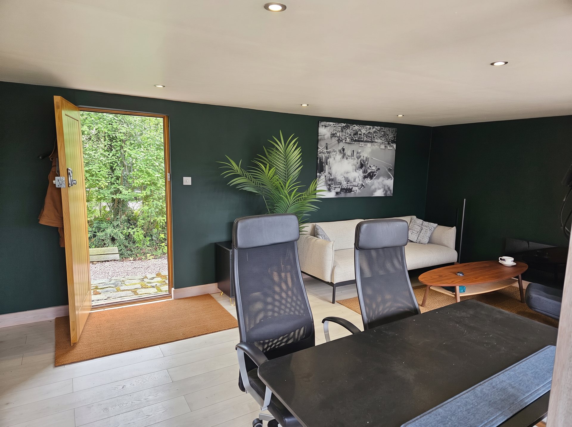 The Oulton Moto Store green room, with deep green walls, an open door to the garden and space to sit and talk